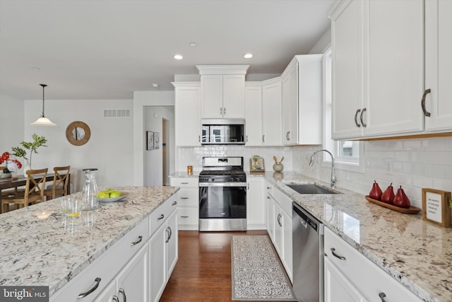 kitchen featuring appliances with stainless steel finishes, sink, white cabinets, dark hardwood / wood-style flooring, and hanging light fixtures