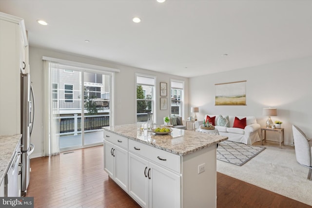 kitchen featuring white cabinetry, dark hardwood / wood-style flooring, light stone countertops, and a kitchen island