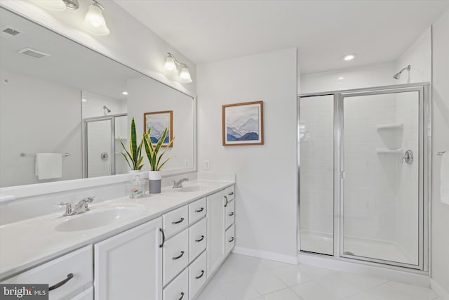 bathroom with a shower with door, vanity, and tile patterned floors