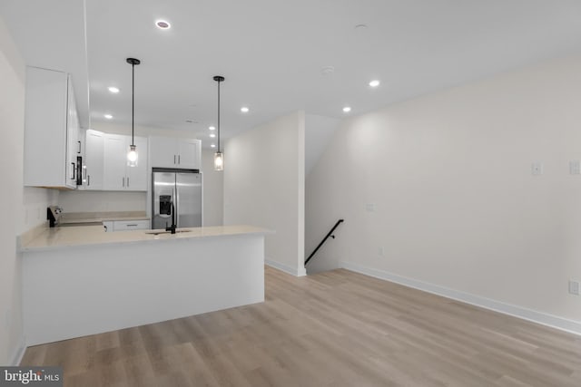 kitchen featuring sink, light hardwood / wood-style flooring, appliances with stainless steel finishes, white cabinetry, and hanging light fixtures