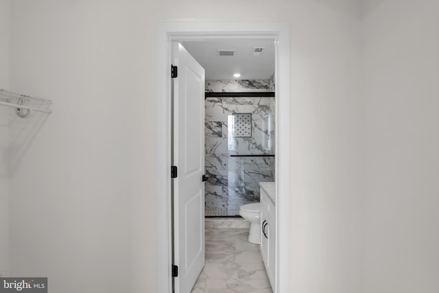 bathroom featuring toilet, vanity, and a shower with shower door