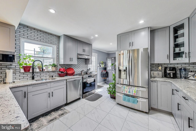 kitchen featuring sink, gray cabinetry, stainless steel appliances, light stone counters, and decorative backsplash