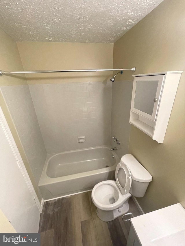 bathroom featuring toilet, a textured ceiling, wood finished floors, and bathing tub / shower combination