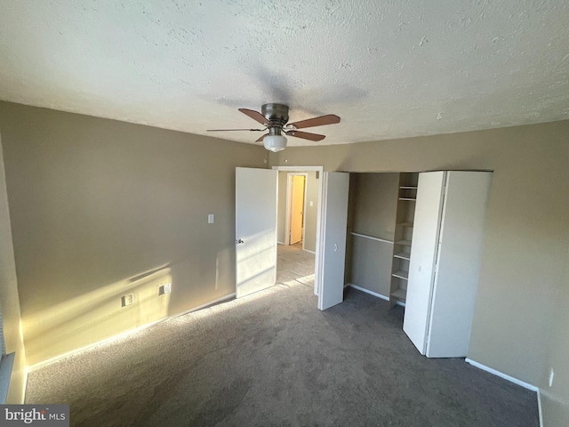 unfurnished bedroom with a textured ceiling, ceiling fan, a closet, and dark carpet