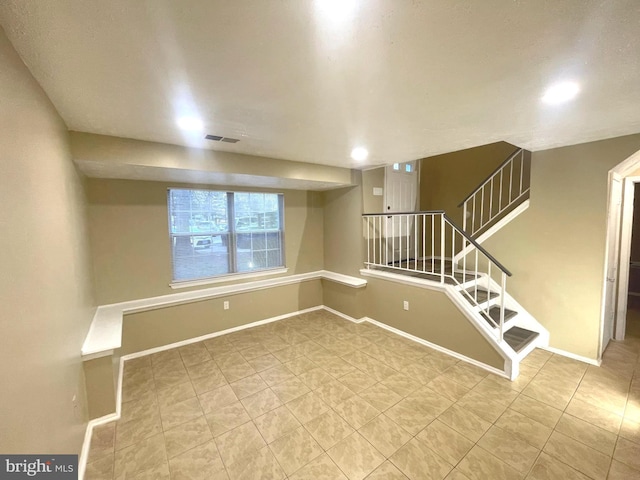 spare room featuring light tile patterned floors, stairway, visible vents, and baseboards