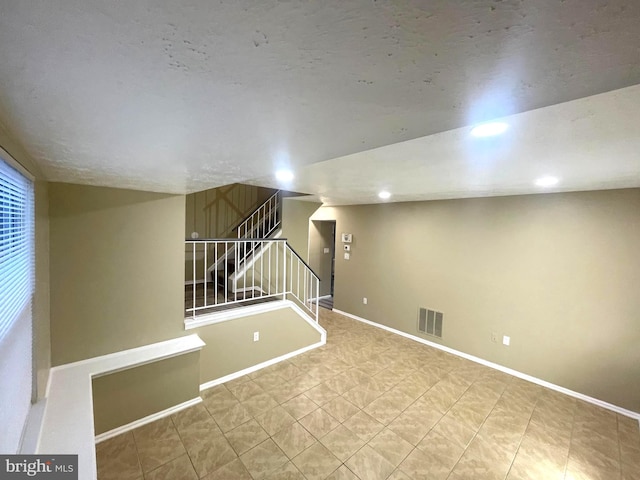 below grade area featuring recessed lighting, visible vents, stairway, and baseboards