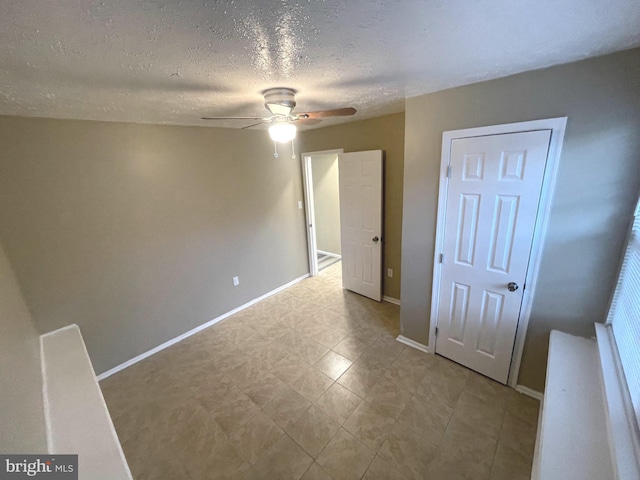 unfurnished bedroom with a ceiling fan, baseboards, and a textured ceiling