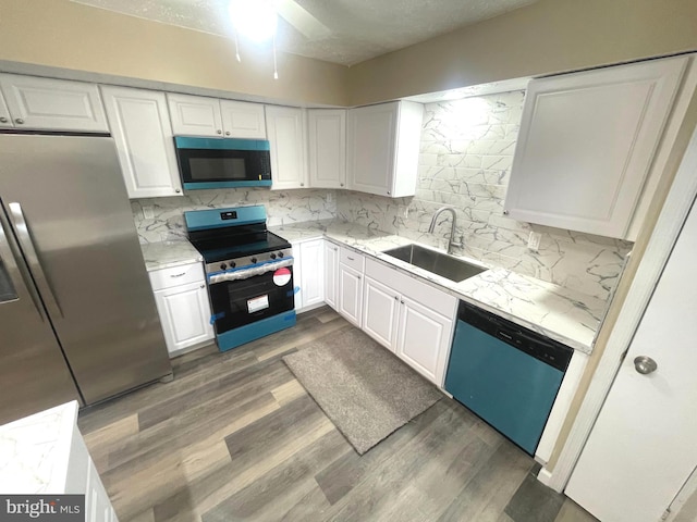 kitchen featuring white cabinets, decorative backsplash, stainless steel appliances, and a sink