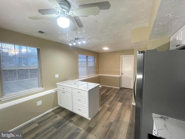 kitchen featuring dark wood-style floors, freestanding refrigerator, white cabinets, a textured ceiling, and light stone countertops