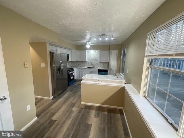 kitchen with dark wood finished floors, stainless steel appliances, tasteful backsplash, white cabinets, and a peninsula