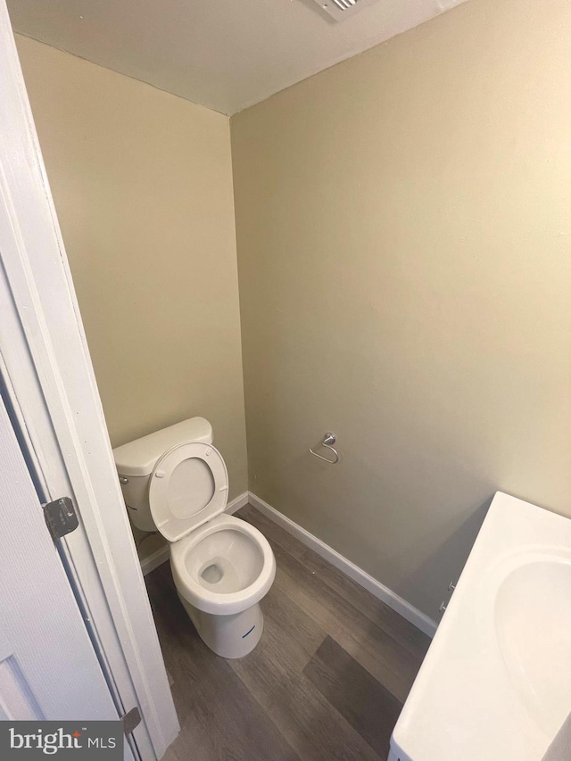 bathroom featuring a sink, wood finished floors, toilet, and baseboards