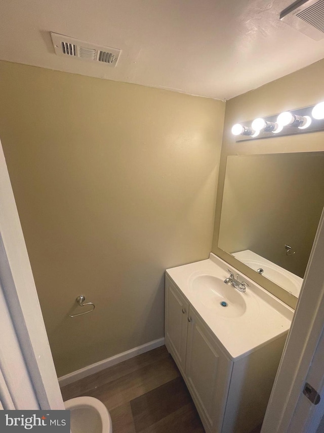 bathroom featuring visible vents, vanity, baseboards, and wood finished floors