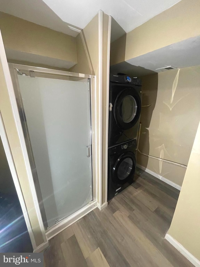 bathroom with baseboards, stacked washer and dryer, wood finished floors, and a shower stall