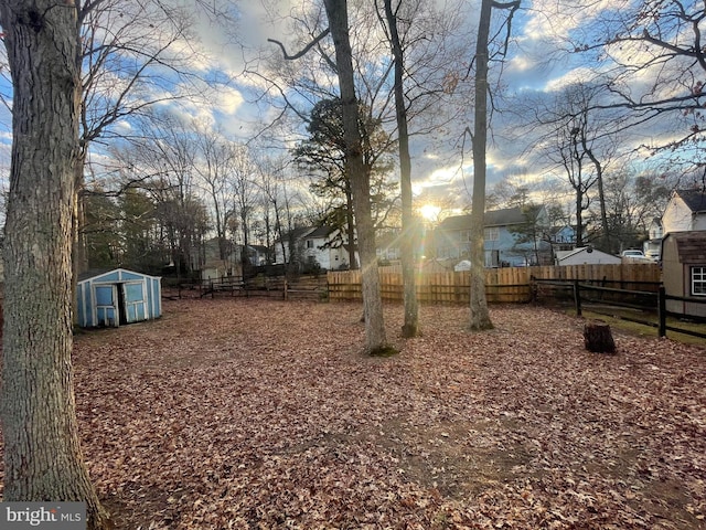 view of yard with an outdoor structure, fence, and a storage unit