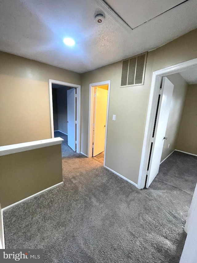 unfurnished room featuring dark carpet, visible vents, and baseboards