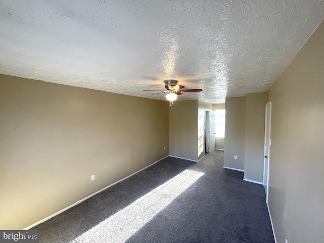 unfurnished room with a ceiling fan, dark colored carpet, a textured ceiling, and baseboards