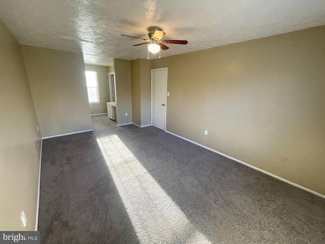 spare room featuring dark carpet, a textured ceiling, baseboards, and ceiling fan