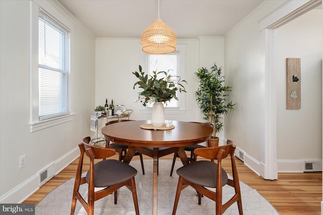 dining room with crown molding, an inviting chandelier, and light hardwood / wood-style flooring