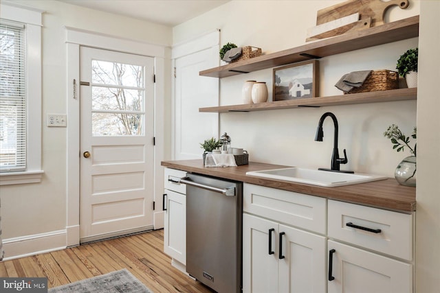 interior space featuring white cabinets, dishwasher, sink, and wooden counters