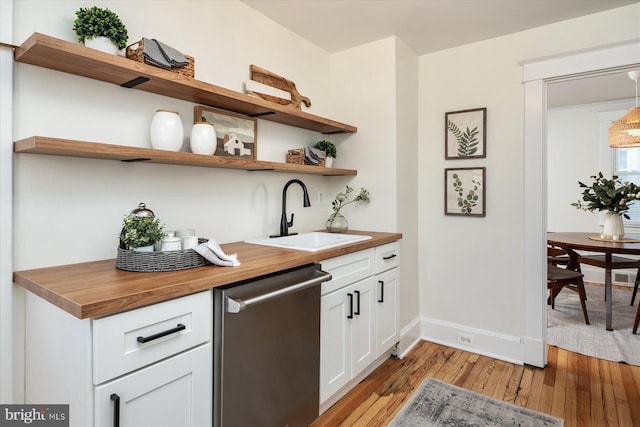 bar featuring wood counters, white cabinetry, sink, stainless steel dishwasher, and light hardwood / wood-style flooring