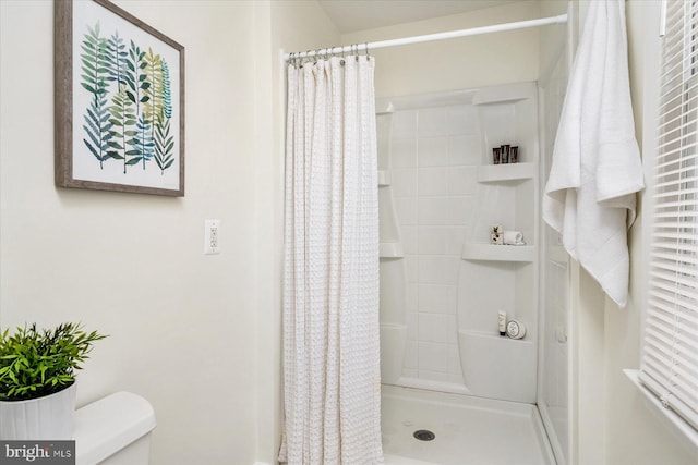 bathroom with toilet and a shower with shower curtain