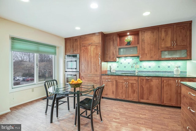 kitchen featuring tasteful backsplash, sink, light hardwood / wood-style flooring, and stainless steel double oven