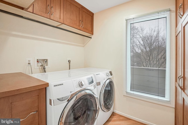 laundry room featuring cabinets, light hardwood / wood-style floors, and washer and dryer