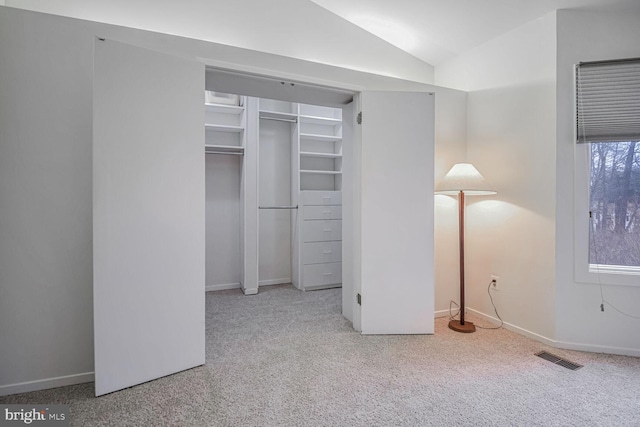 unfurnished bedroom with vaulted ceiling, light colored carpet, and a closet