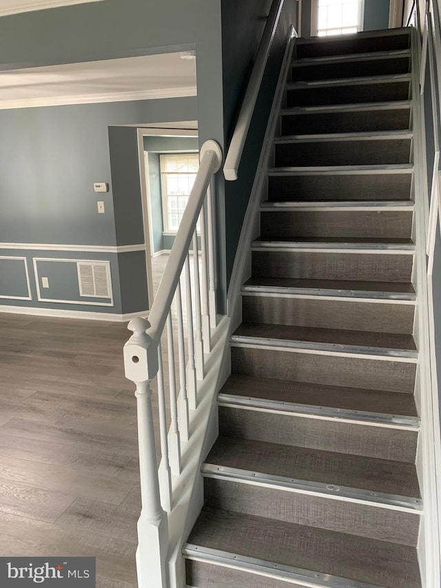 stairs with hardwood / wood-style flooring and ornamental molding