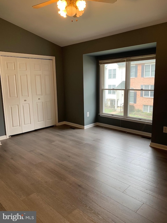 unfurnished bedroom with vaulted ceiling, ceiling fan, hardwood / wood-style floors, and a closet