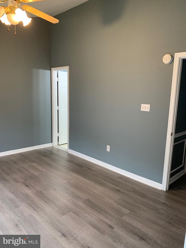 empty room featuring ceiling fan, hardwood / wood-style floors, and a high ceiling