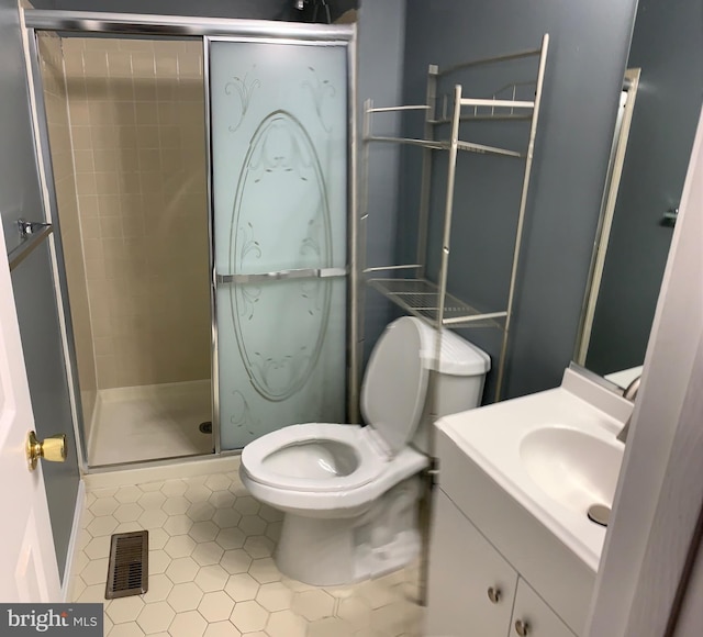 bathroom with vanity, a shower with shower door, tile patterned floors, and toilet