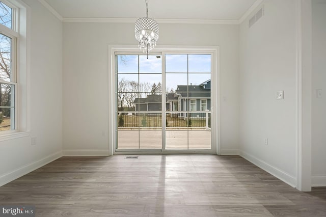 unfurnished dining area with ornamental molding, hardwood / wood-style floors, and an inviting chandelier