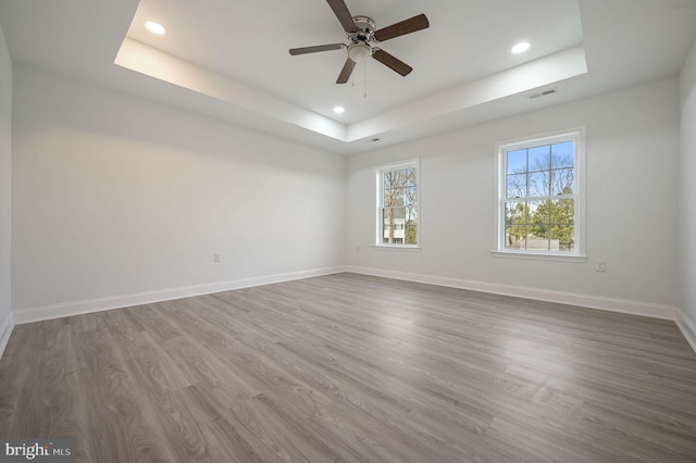 spare room with a tray ceiling, dark hardwood / wood-style floors, and ceiling fan