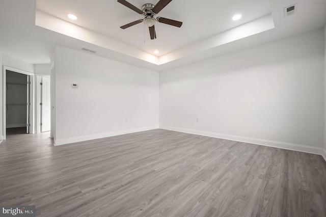 spare room featuring hardwood / wood-style floors, a tray ceiling, and ceiling fan