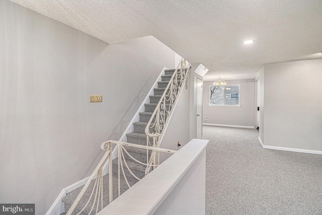 stairs featuring a textured ceiling and carpet flooring