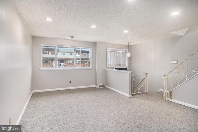 unfurnished room featuring a textured ceiling and carpet