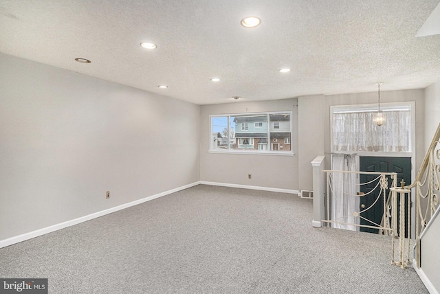 unfurnished living room with carpet flooring and a textured ceiling