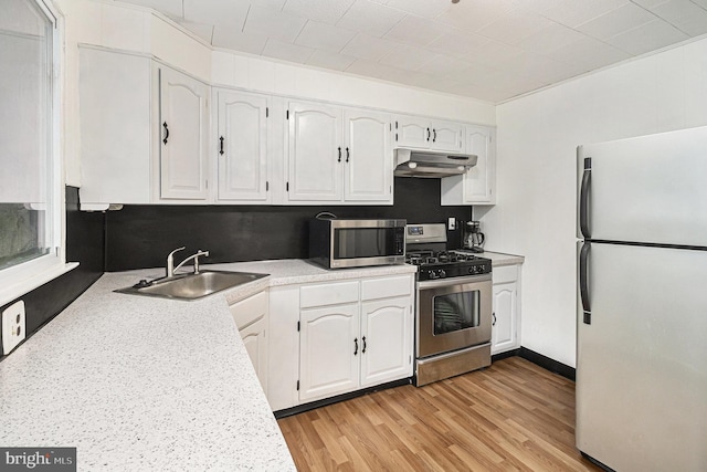 kitchen with sink, light wood-type flooring, white cabinets, and appliances with stainless steel finishes