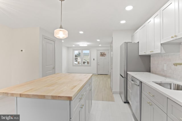 kitchen featuring a kitchen island, sink, wooden counters, white cabinets, and stainless steel appliances