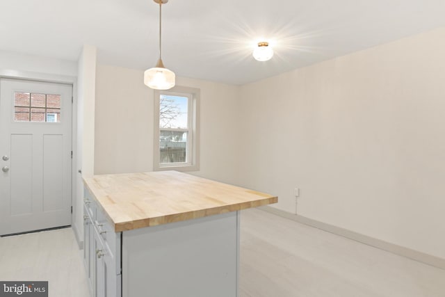 kitchen featuring light hardwood / wood-style floors, butcher block countertops, and hanging light fixtures