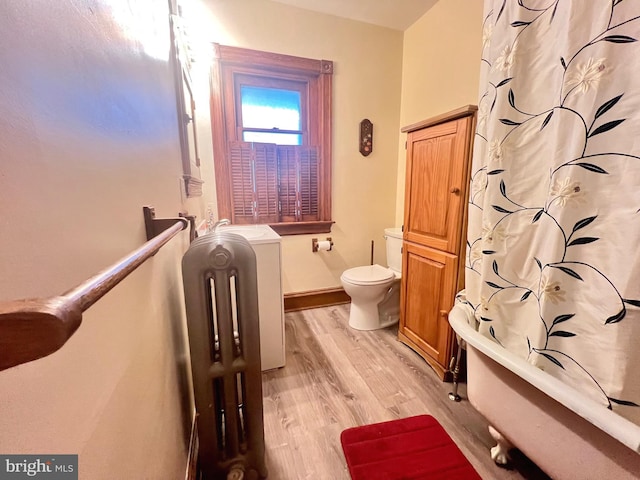 bathroom with wood-type flooring, shower / bath combo, and toilet