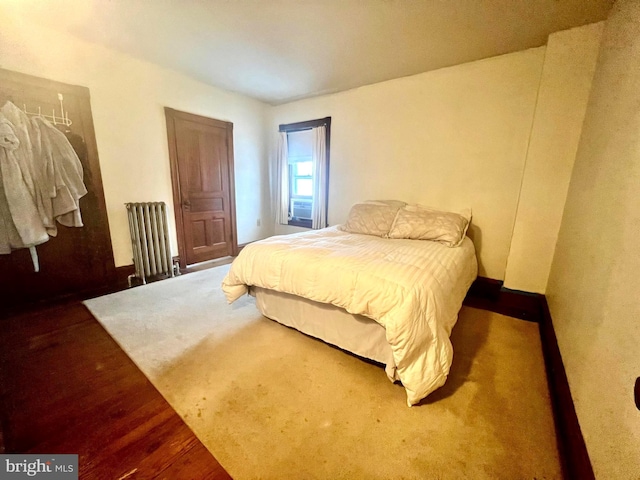 bedroom with hardwood / wood-style flooring and radiator heating unit