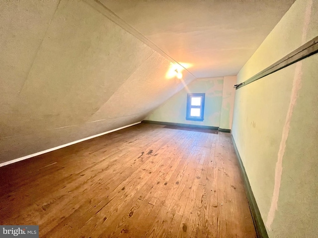 additional living space featuring lofted ceiling, wood-type flooring, and a barn door