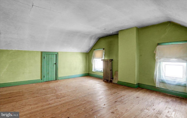 additional living space with lofted ceiling, light hardwood / wood-style flooring, and a healthy amount of sunlight