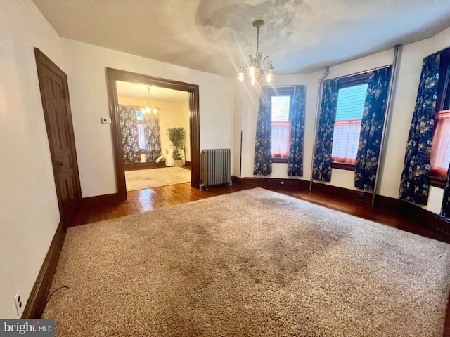 unfurnished dining area featuring radiator, hardwood / wood-style floors, and a notable chandelier