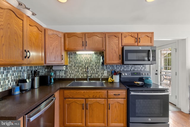 kitchen with stainless steel appliances, tasteful backsplash, sink, and light hardwood / wood-style flooring