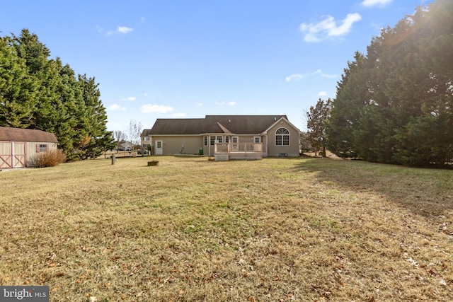 back of property with a wooden deck, a yard, and a shed