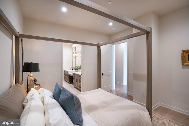 bedroom featuring connected bathroom and light hardwood / wood-style flooring