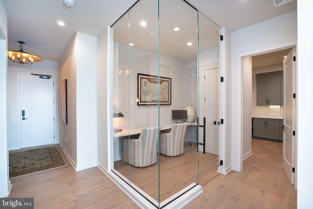 hall with a notable chandelier and light hardwood / wood-style floors